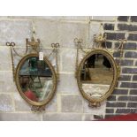 A pair of Edwardian Adam design giltwood and composition oval wall mirrors with swagged urn