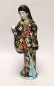 A Japanese porcelain figure of a geisha girl wearing a floral blue ground kimono, 27cm tall