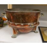 A large copper and brass two handled pail, raised on lion paw supports, 60cm wide including handles