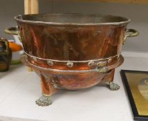 A large copper and brass two handled pail, raised on lion paw supports, 60cm wide including handles