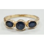 A modern 585 yellow metal and three stone sapphire set ring, size O, gross weight 2.4 grams.