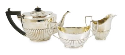 A late Victorian oak cased demi-fluted oval silver three piece tea set, by Martin, Hall & Co,