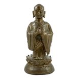 A Chinese bronze figure of a standing luohan, late Ming dynasty, depicted wearing long flowing