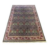 A large Indian Arts & Crafts style carpet, with stylised pomegranate and flower motifs on a charcoal