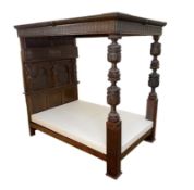 A 17th century style oak tester bedstead, with gadrooned panelled canopy on cup and cover front