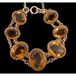 An early 20th century 9ct gold and graduated seven stone oval cut citrine set bracelet,