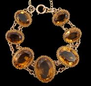 An early 20th century 9ct gold and graduated seven stone oval cut citrine set bracelet,