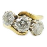 A modern 18ct gold and three stone diamond set crossover ring, the central stone approximately 0.