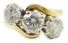 A modern 18ct gold and three stone diamond set crossover ring, the central stone approximately 0.