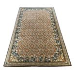 A large Indian carpet, with foliate trellis ribbon and paterae motifs across a pale brown ground,