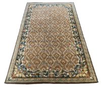 A large Indian carpet, with foliate trellis ribbon and paterae motifs across a pale brown ground,