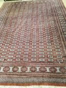 A Bokhara style burgundy ground carpet, 360 x 280cm