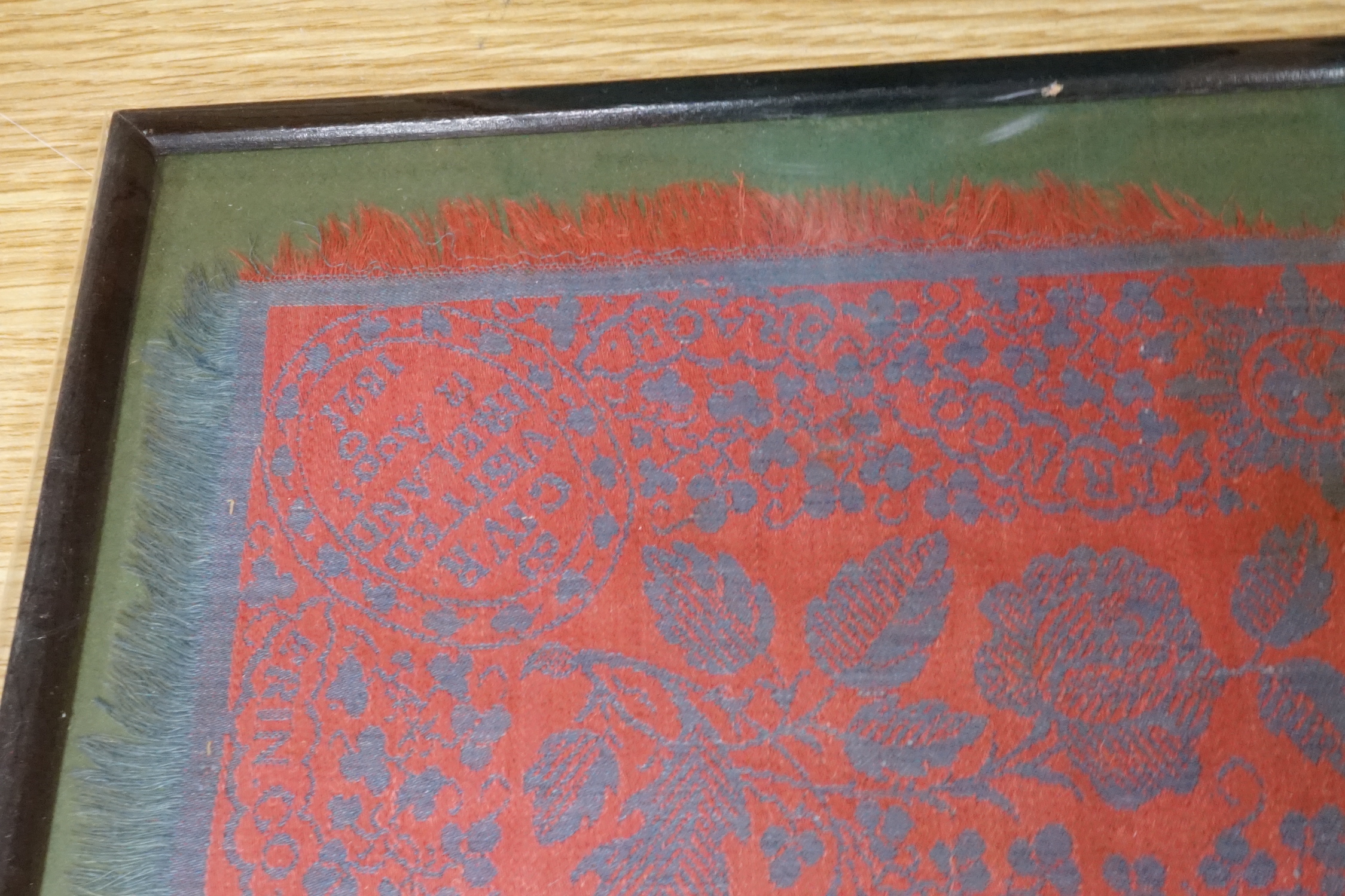 An unusual framed George IV Irish damask napkin, designed with a red ground and blue woven floral - Image 2 of 3