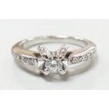 A modern 18ct white gold and claw set single stone diamond ring, with diamond chip set shoulders,