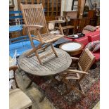 A circular weathered teak folding garden table, diameter 100cm, height 73cm and two elbow chairs