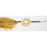 A large Chinese bowenite jade disc, threaded with tiger's eye beads and long silk tassel, 90cm long