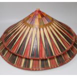 Three red and black striped bamboo rice hats, together with a smaller rice hat with beaded flag