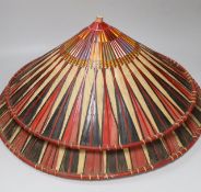 Three red and black striped bamboo rice hats, together with a smaller rice hat with beaded flag