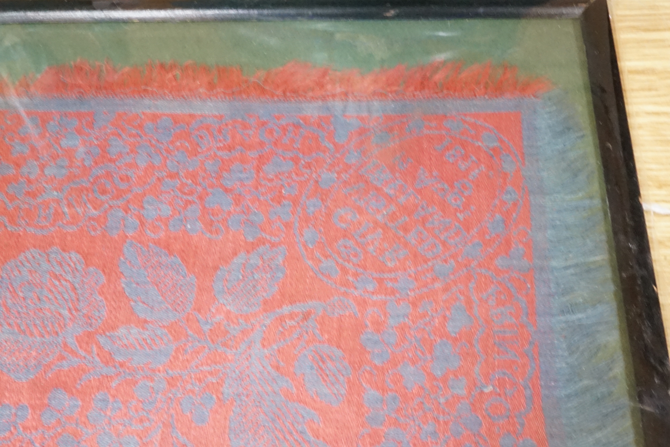 An unusual framed George IV Irish damask napkin, designed with a red ground and blue woven floral - Image 3 of 3