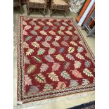 A Portuguese polychrome red ground rug woven with stylised leaves 236cm x 170cm.