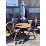 A Royal Craft teak folding table and four chairs with two cushions, parasol and cast metal base,