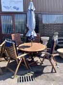 A Royal Craft teak folding table and four chairs with two cushions, parasol and cast metal base,