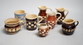 Eight 19th century slip-decorated creamware chequer-pattern jugs and mugs, tallest 10cm