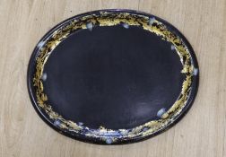 A Regency oval gilt and japanned papier mache tray, designed with a thistle border, 63cm wide