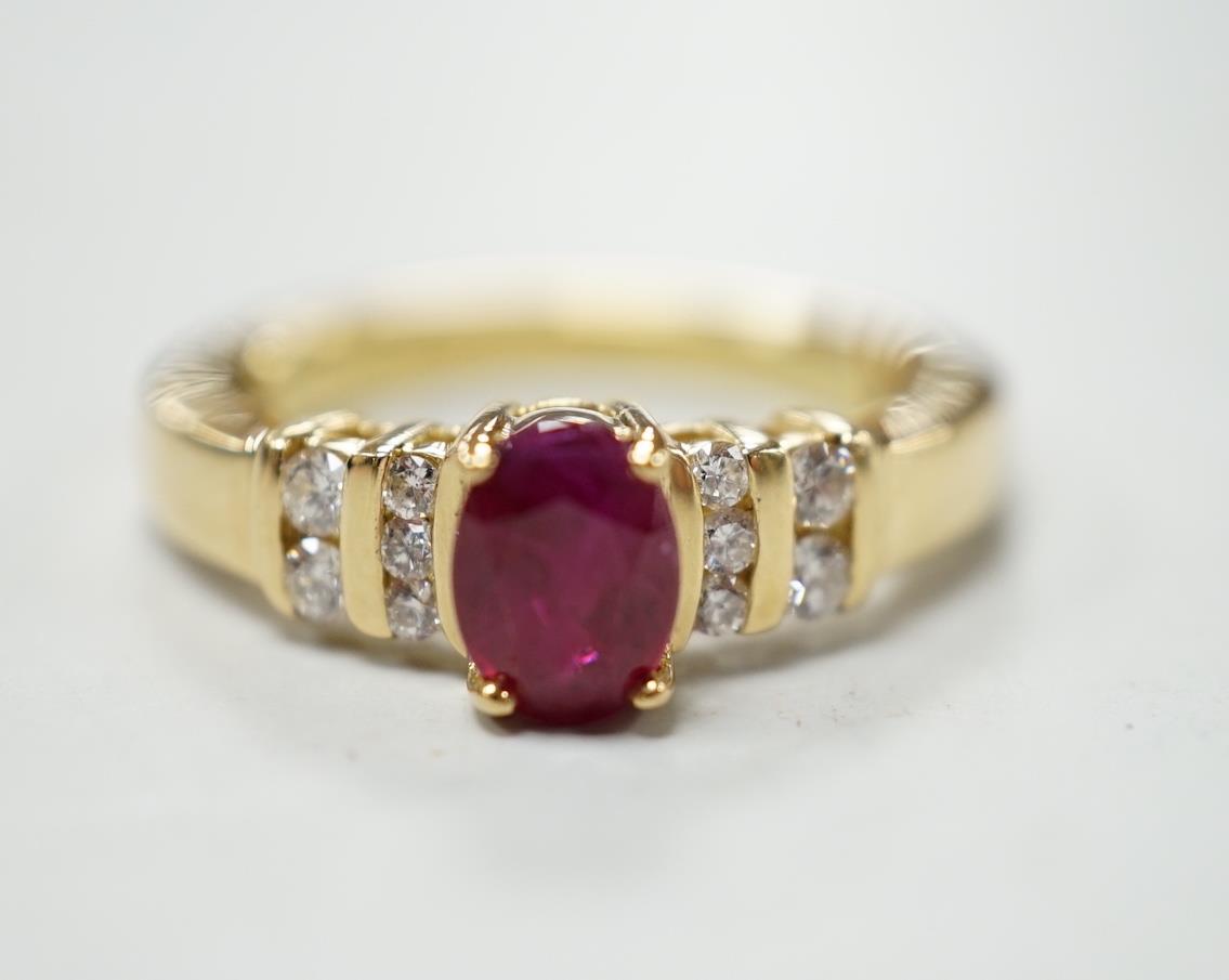 A modern yellow metal and single stone oval cut ruby set dress ring, with ten stone diamond chip set