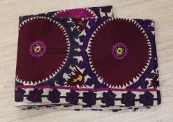 A Suzani hanging, embroidered with two rows of aubergine roundels, 255 x 90cm