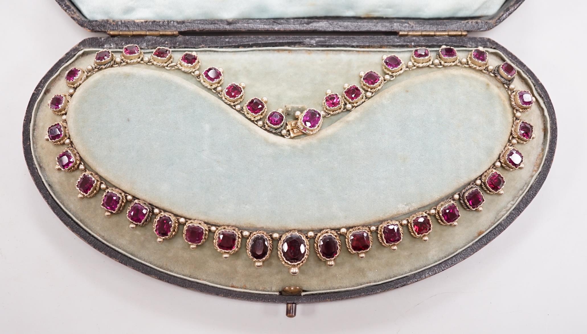 A cased 19th century gilt white metal and graduated oval and square cut garnet set fringe