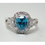 A modern 14k white metal, cushion cut blue zircon and diamond chip set cluster dress ring, with