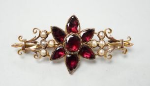 A late Victorian yellow metal, foil backed garnet and split pearl set flower head bar brooch,