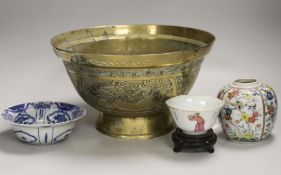 An early 20th century Chinese famille rose tea bowl and stand together with a brass ‘dragon’ bowl, a