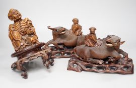 A pair of Chinese carved hardwood buffalo carvings, and a similar figure of a luohan, latter