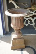 A Victorian style cast iron campana garden urn on a square plinth, diameter 38cm, height 68cm