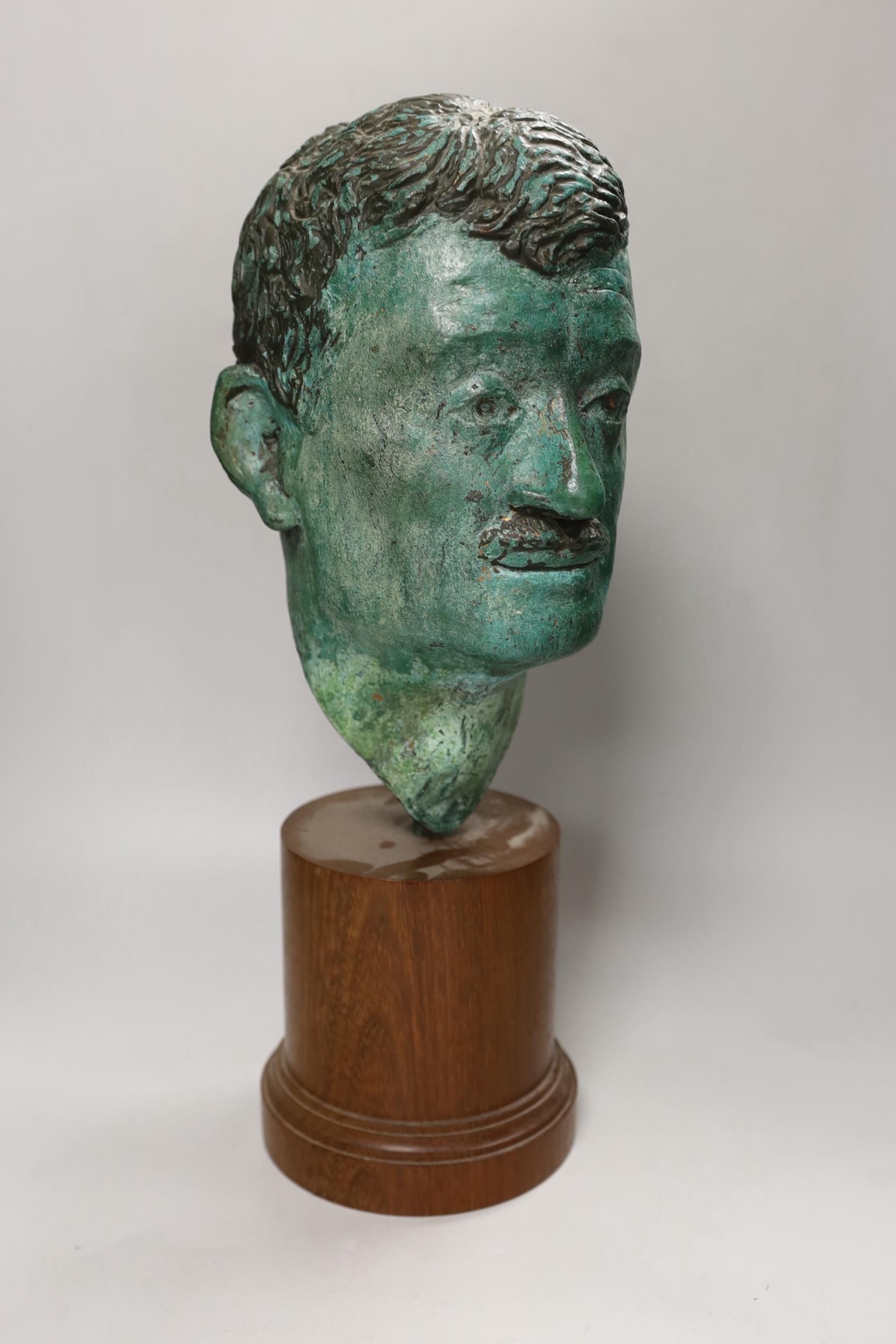 A verdigris metal head of a gentleman mounted on a wooden stand, 48cm high