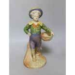 A Royal Worcester figure of a boy with a basket and a broad brimmed hat painted in shot enamels