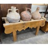 Three Mediterranean pottery olive jars on a rectangular pine stand, stand width 116cm, depth 41cm,