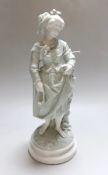 A celadon glazed figure of a girl, barefooted beside a tree, holding her skirt off the ground, c.