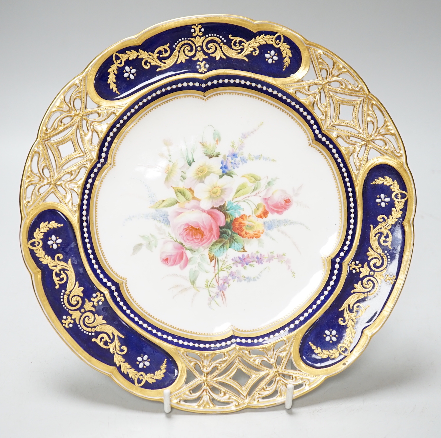 A Coalport plate with pierced border enamelled with white flowers and neo-classical raised paste