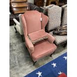 An upholstered wing armchair and footstool