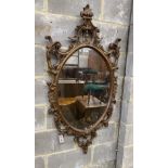 A Victorian style oval composition carved wall mirror, width 66cm, height 130cm