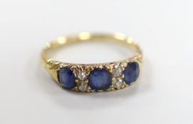 A late Victorian 18ct gold, three stone sapphire and four stone diamond chip spacer set half hoop
