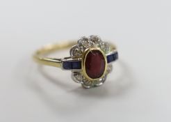 A 1920's/1930's yellow metal, ruby, sapphire and diamond set oval cluster ring, size O, gross weight