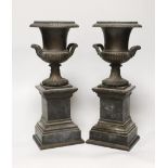 A pair of late 19th century bronze campana urns on rectangular pedestals, each 32cm high