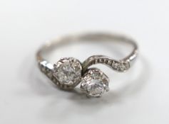 A white metal and two stone diamond set crossover ring, with diamond chip set shoulders, size P,