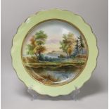 A mid 19th century English pottery charger painted with a coastal landscape under a light green