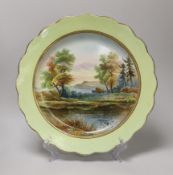 A mid 19th century English pottery charger painted with a coastal landscape under a light green