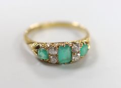 A late Victorian 18ct gold, three stone emerald and four stone diamond spacer set half hoop ring,